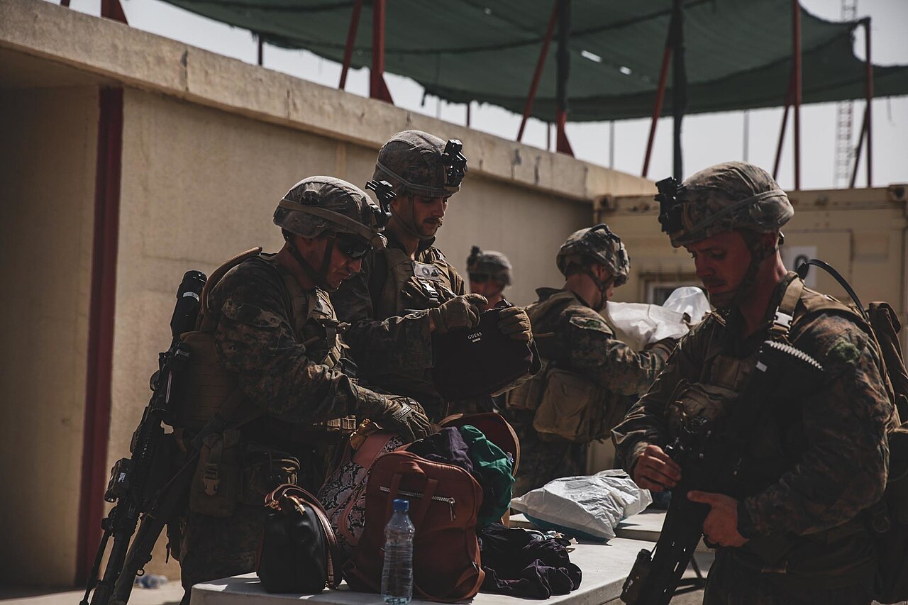 Marines with the 24th Marine Expeditionary Unit (MEU) search luggage during an evacuation at Hamid Karzai International Airport, Kabul, Afghanistan, Image 6 of 8