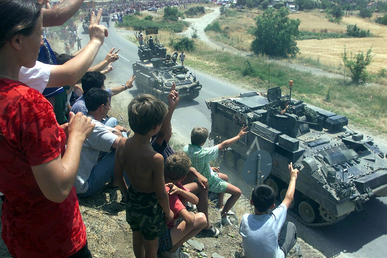 WARRIOR ARMOURED PERSONNEL CARRIERS ARE CHEERED ON AS THEY PASS REFUGEES. SOUTHERN KOSOVO BORDER. 12-09-1999 MOD 45108827