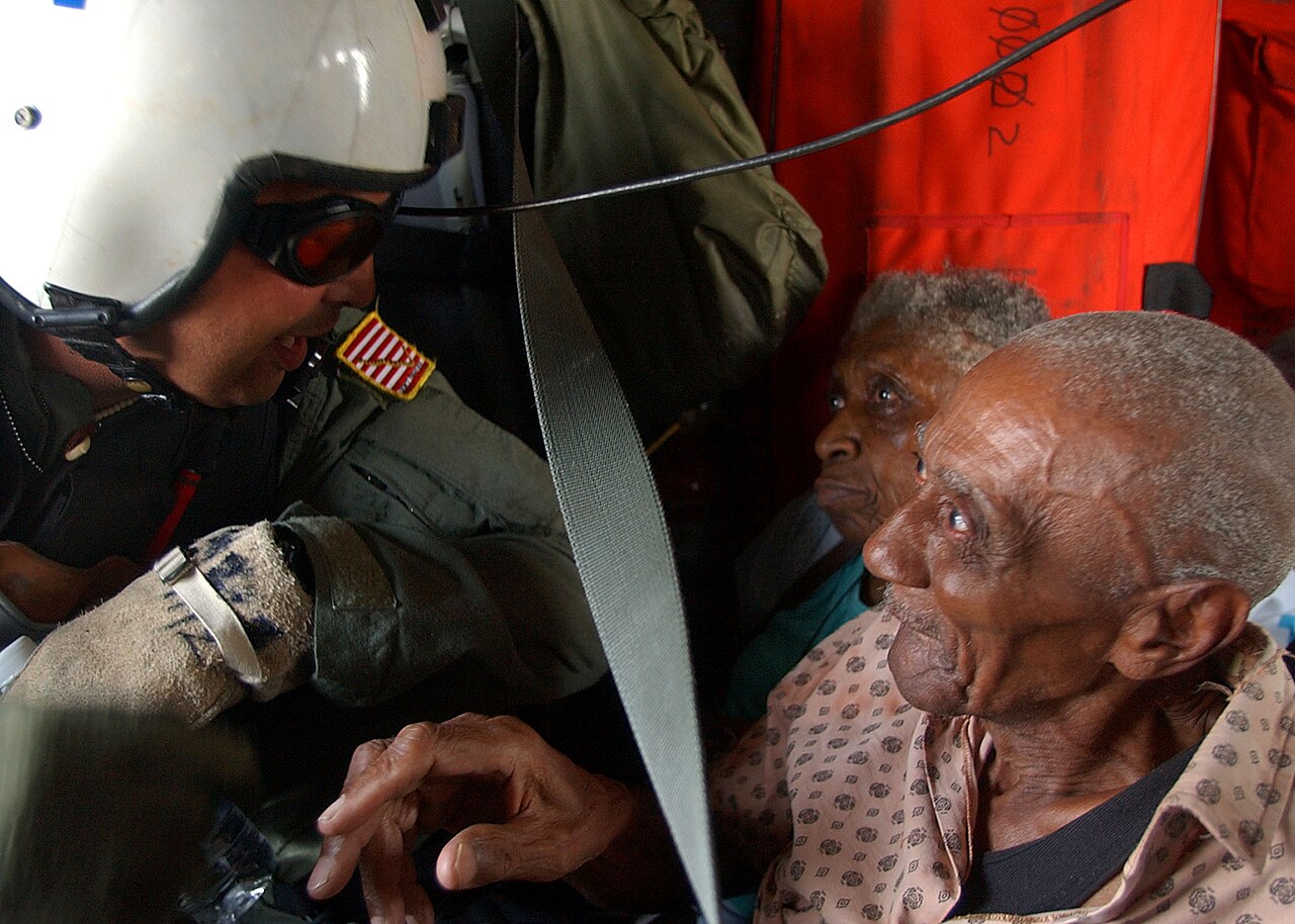 US Navy 050902-N-0535P-251 Navy Search and Rescue (SAR) Swimmer Aviation Warfare Systems Operator 1st Class Scott Chun calms victims of Hurricane Katrina after rescuing them from a